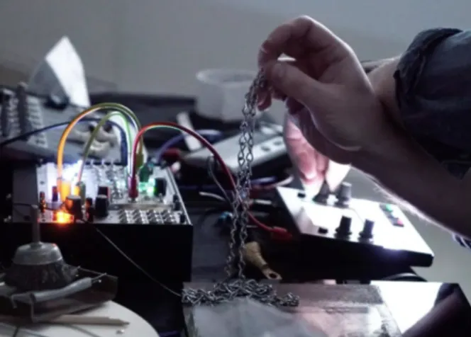 Hand holding chain over synthesizer