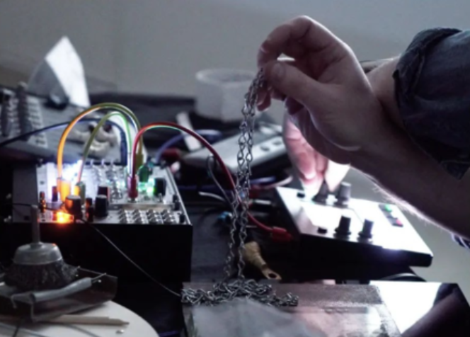 Hand holding chain over synthesizer