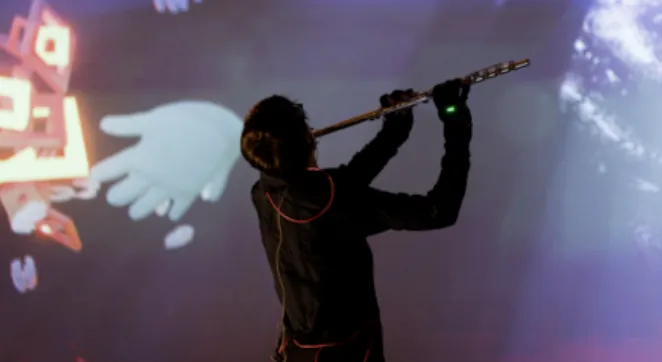 Person playing flute in front of projected screen