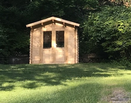 A small brown shack on a green lawn.