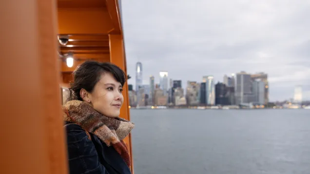 Kitty Xiao, composer, staring into the distance with a city skyline in the background